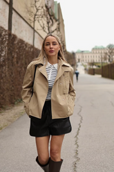 a lady wears a black and white striped jumper with a cropped trench coat